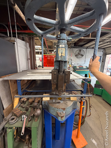 A different fly press. It has two pieces of wood supporting the bar as widely as possible so that the bend is gradual, rather than abrupt